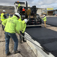 Treasure State Concrete, Inc. crew placing fresh asphalt along a concrete curb